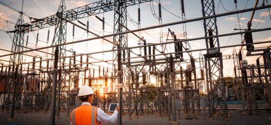 Worker standing in front of large outdoor substation