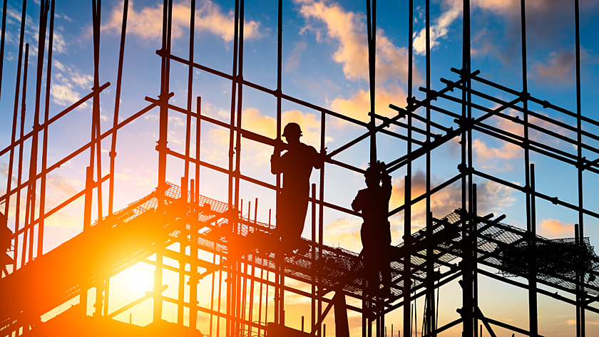Sunset photograph of construction workers standing on scaffolding