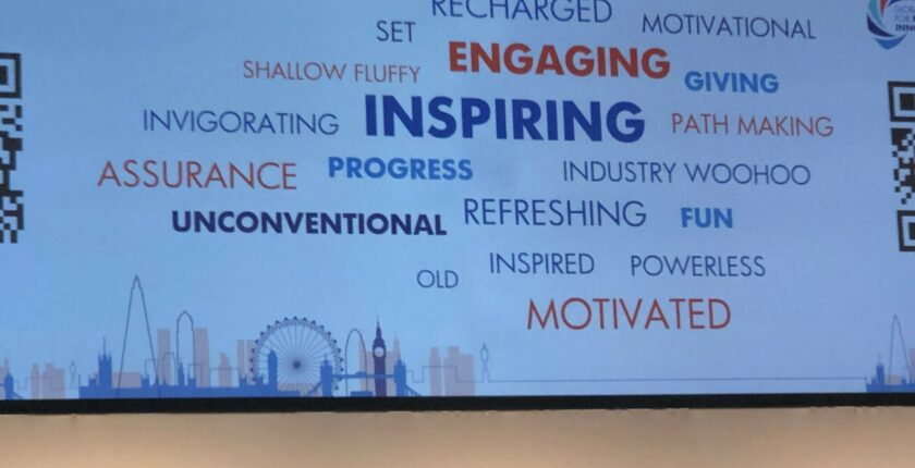 Photograph of a powerpoint presentation showcasing a cloud of keywords: recharged, motivational, set, engaging, giving, shallow fluffy, invigorating, inspiring, path making, assurance, progress, industry woohoo, unconventional, refreshing, fun, inspired, old, powerless. and motivated