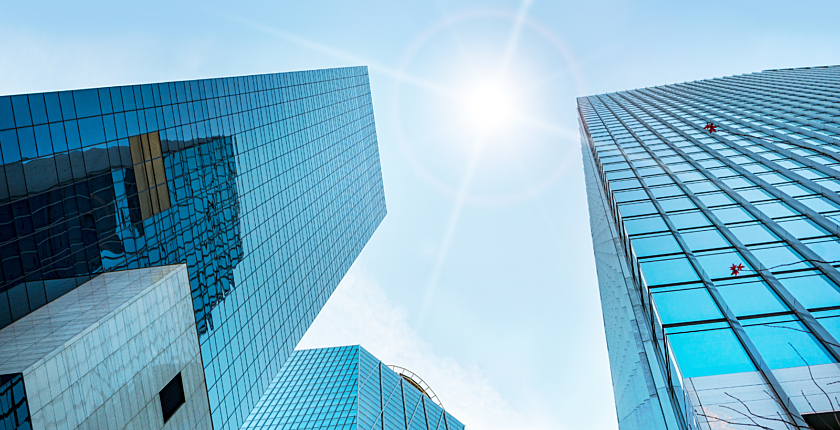 Photograph of the sun shining down on multiple skyscrapers