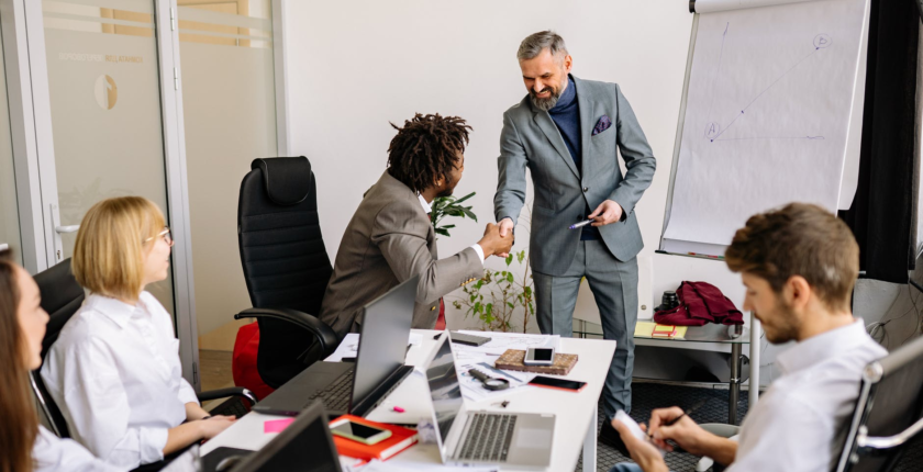 Workers shaking hands after a successful pitch presentation
