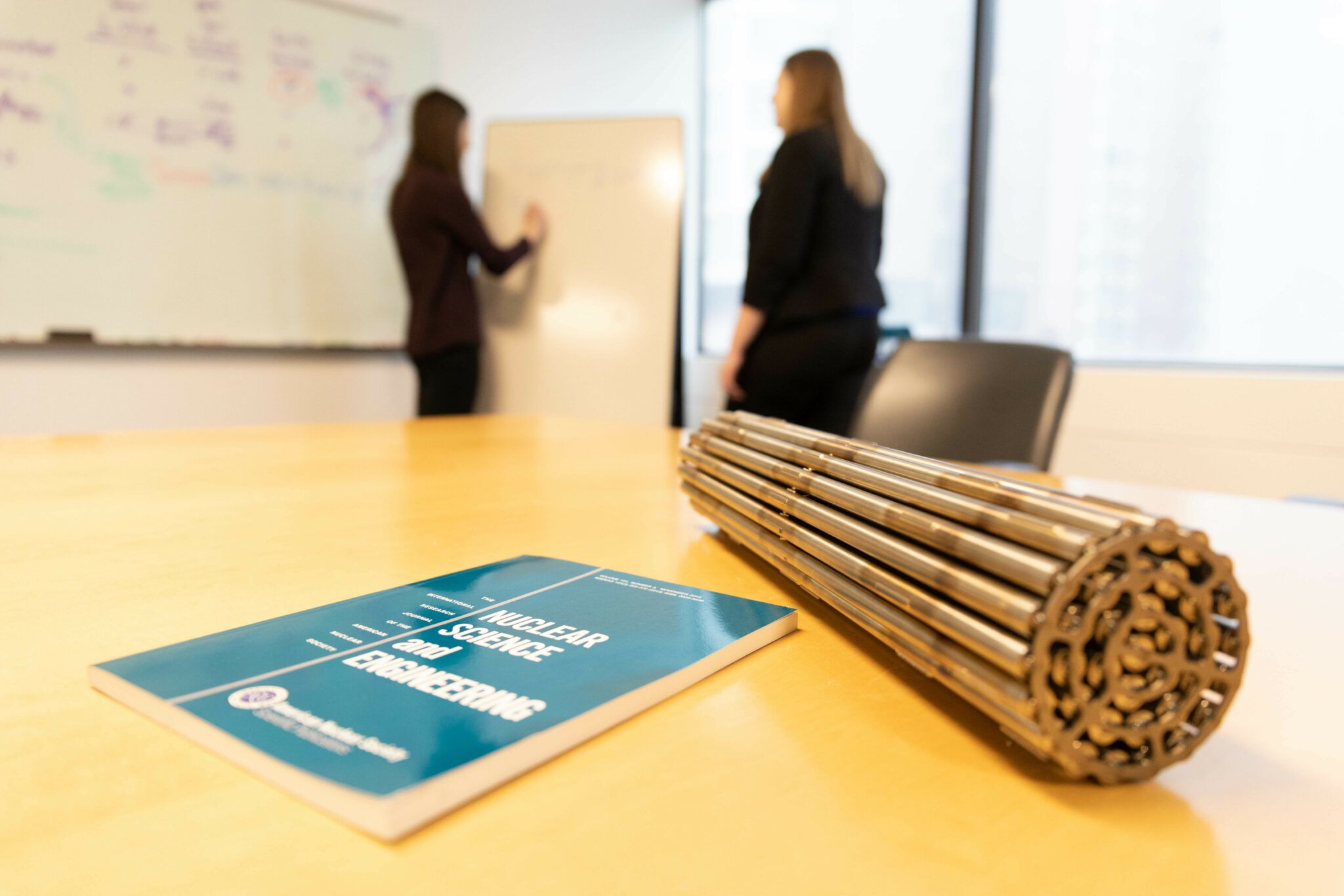 Closeup of a CANDU fuel bundle alongside textbook on a desk