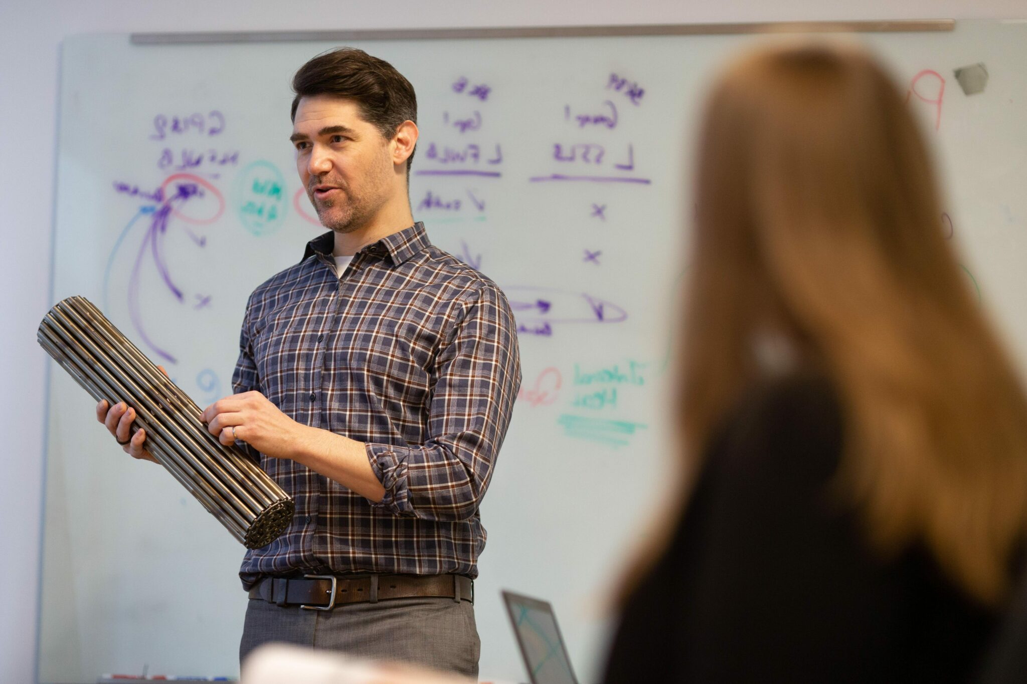 Person teaching audience while holding machine part
