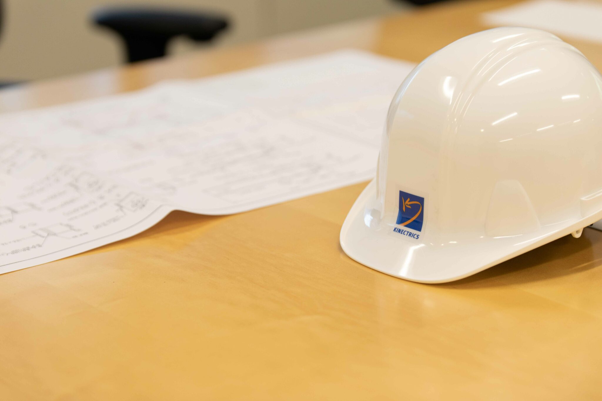 A hardhat and some design drawings on a table