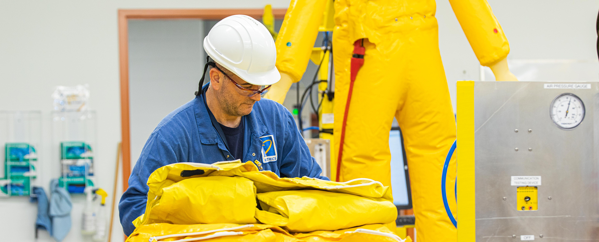 Industrial worker folding plastic protective suits for inspection.